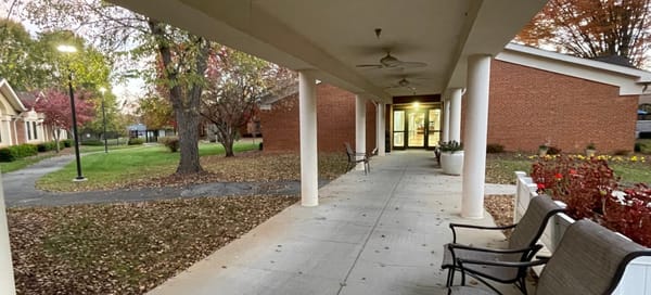 A breezeway to a skilled nursing facility, with autumn leaves on the grass next to the breezeway